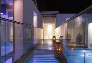 Night view of a modern glass walkway with lanterns and ambient lighting at Camping Union Lido Mare in Veneto, Italy.