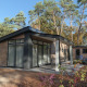 Forest park chalet 8p i Holiday park De Kleine Belties, Nederlandene, omgivet af grønne træer.