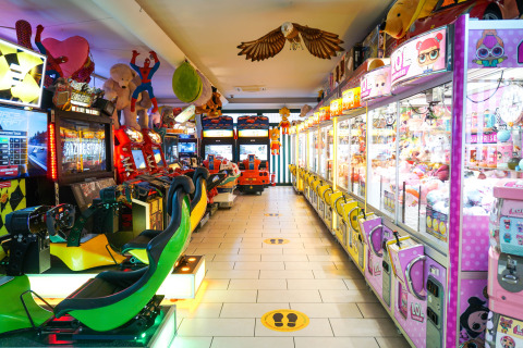 Sala giochi con macchine arcade e acchiappapremi al Camping Union Lido Mare, Veneto, Italia.