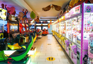 Sala giochi con macchine arcade e acchiappapremi al Camping Union Lido Mare, Veneto, Italia.