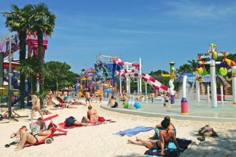 Ospiti si rilassano e bambini giocano nel parco acquatico di Camping Union Lido Mare, Veneto, Italia.