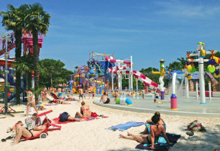 Solrige gæster slapper af og leger ved vandlandet i Camping Union Lido Mare i Veneto, Italien.