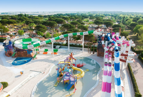 Toboganes acuáticos coloridos y zona de juegos en Camping Union Lido Mare, un parque de vacaciones en Véneto, Italia.