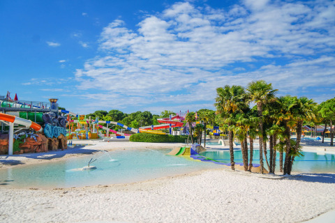 Vandland med rutsjebaner, palmer og pool i ferieparken Union Lido Mare ved stranden i Veneto, Italien.