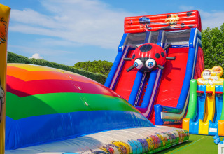 Farverig hoppborg og oppustelige rutsjebaner på Union Lido Mare feriepark i Veneto, Italien, under klar himmel.
