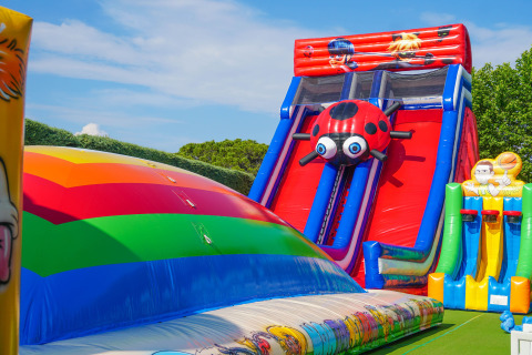 Colorful bouncy castle and inflatable slides at Union Lido Mare holiday park in Veneto, Italy, on a sunny day.