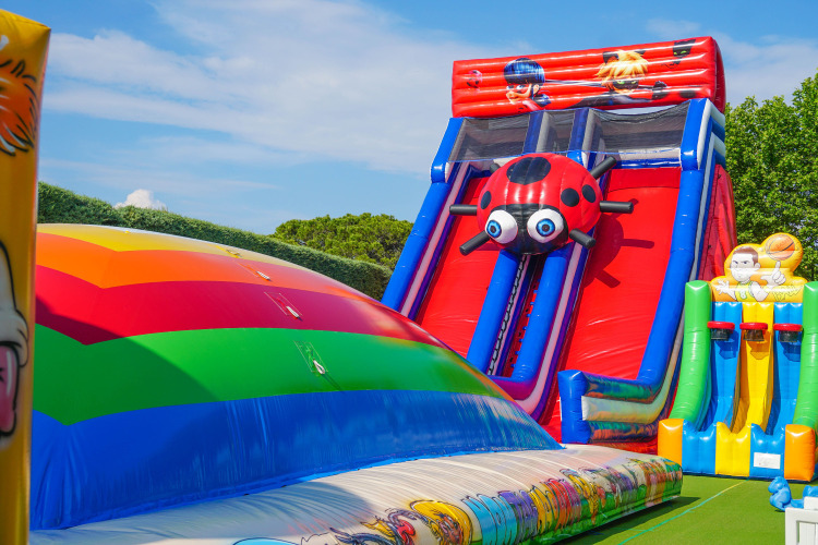 Colorful bouncy castle and inflatable slides at Union Lido Mare holiday park in Veneto, Italy, on a sunny day.