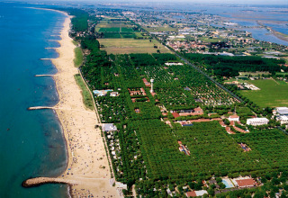 Luftfoto af Camping Union Lido Mare feriepark ved stranden i Veneto, Italien, omgivet af grønt område.