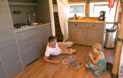 Padre e hija juegan un juego de mesa en el suelo de la cocina en Sunlodge Safari, Camping Union Lido Mare, Italia.