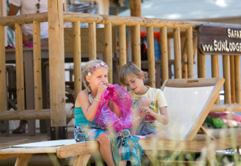 Due bambini si rilassano al Sunlodge Safari al Camping Union Lido Mare in Italia, uno gonfia un palloncino.