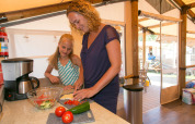 Mother and daughter preparing a fresh meal together in a luxury glamping accommodation kitchen tent.