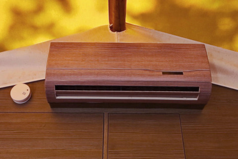 Aire acondicionado y detector de humo en la pared de madera de una tienda glamping con fondo soleado.