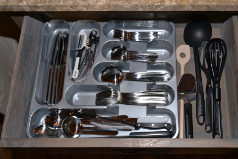Cajón organizado con cubiertos y utensilios, como cucharas, tenedores y cuchillos en alojamiento glamping.