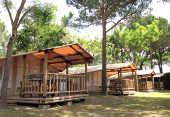 SunLodge Jungle al Camping Union Lido Mare in Italia, con lodge in legno sotto alberi verdi e ambiente naturale.