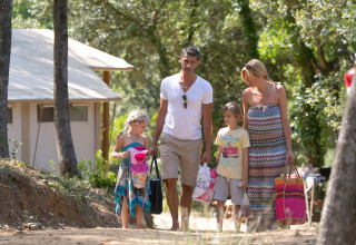 Een familie wandelt op het pad bij SunLodge Jungle aan Camping Union Lido Mare in Italië, tussen bomen.