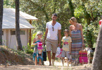 Une famille marche sur un sentier à SunLodge Jungle au Camping Union Lido Mare en Italie, entourée d’arbres.