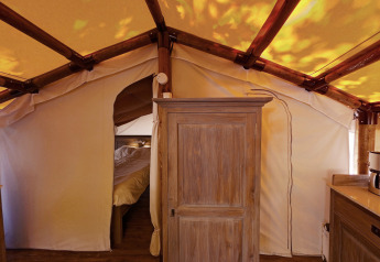 Intérieur de la SunLodge Jungle avec armoire en bois, lit à l'arrière-plan et structure de tente en toile.