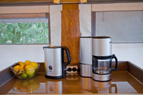 Macchina del caffè, bollitore elettrico e ciotola di frutta sul piano cucina a SunLodge Jungle, Camping Union Lido Mare, Italia.
