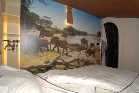 Camera al SunLodge Jungle presso Camping Union Lido Mare, Italia, con murale di elefanti sulla parete.