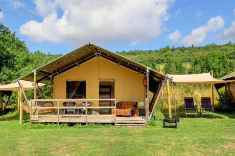 Lodge de tienda safari en medio de la naturaleza, con terraza de madera y sillas exteriores cómodas.