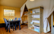 Innenraum eines Safari-Zelts auf Camping Walsheim in Deutschland mit Tisch, Stühlen und Etagenbett.