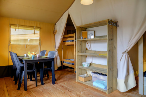 Interno di una tenda Safari al Camping Walsheim in Germania con tavolo, sedie, letto a castello e scaffale.