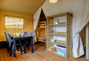 Interno di una tenda Safari al Camping Walsheim in Germania con tavolo, sedie, letto a castello e scaffale.