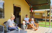 Familia relajándose en la terraza de una tienda tipo safari en Camping Walsheim, Alemania, al aire libre.