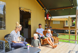 Familia relajándose en la terraza de una tienda tipo safari en Camping Walsheim, Alemania, al aire libre.