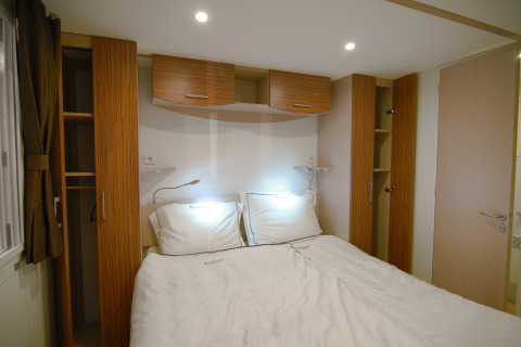 Chambre glamping SunLodge Redwood avec lit double, armoires en bois et éclairage encastré.