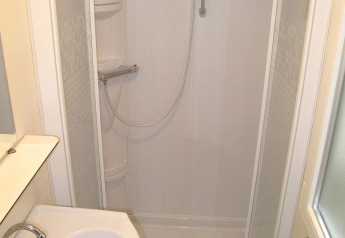 Salle de bain dans l'hébergement glamping SunLodge Redwood avec douche, lavabo et miroir.