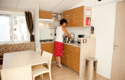Vrouw aan het werk in de keuken van SunLodge Redwood Premium op Camping Union Lido Mare, Italië.