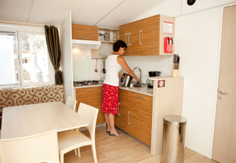 Woman working in the kitchen at SunLodge Redwood Premium, Camping Union Lido Mare, Italy.