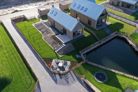 Luchtbeeld van Villa Oesterdam Royal tiny house op Oesterdam Resort in Nederland met vijver en grasvelden.