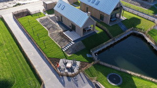 Vista aérea de la tiny house Villa Oesterdam Royal en Oesterdam Resort, Países Bajos, con estanque y jardines.