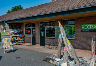 Buitenaanzicht van RECRA vakantiepark met glamping, winkel en kleurrijke decoratie aan de ingang.