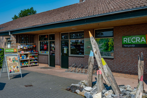 Buitenaanzicht van RECRA vakantiepark met glamping, een winkel en kleurrijke decoraties bij de ingang.