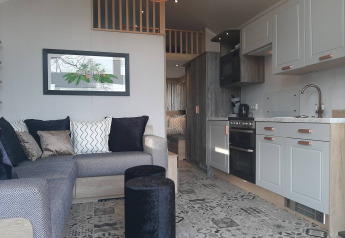 Interiør af et Tiny House-lodge med sofa, farverige puder, køkken og moderne mønstrede gulvfliser.