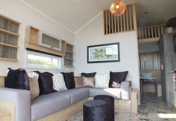 Knusse woonkamer in een Tiny House lodge met grote hoekzetel, sierkussens en een gezellige mezzanine.