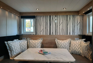 Modernes Sitzbereich mit Kissen und Marmortisch im Tiny house Lodge, helle Gestaltung und Fenster.