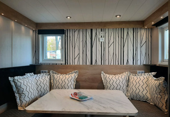 Coin repas moderne dans le lodge Tiny house avec coussins à motifs, mur décoratif et table en marbre.
