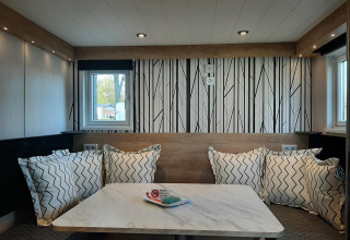 Moderne opholdsområde i Tiny house lodge med træbord, komfortable puder og stilfuld vægdekoration.