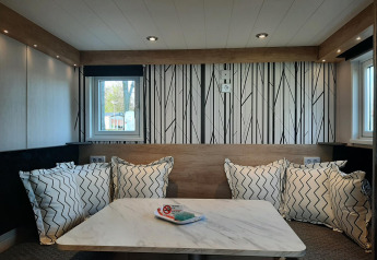 Moderne opholdsområde i Tiny house lodge med træbord, komfortable puder og stilfuld vægdekoration.