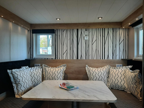 Coin repas moderne dans le lodge Tiny house avec coussins à motifs, mur décoratif et table en marbre.