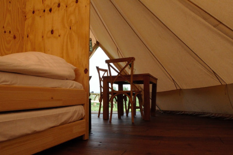 Het interieur van een safari-tent met houten meubels bij Smûk Grutte Bell Tent, Smûk Recreatie, Nederland.
