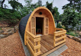 Gemütliche Holzhütte im Ferienpark Camping Roland, Limburg, Niederlande, umgeben von Wald.