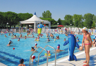 Legende børn og voksne nyder solen i en livlig swimmingpool i Camping Village Marina di Venezia, Italien.