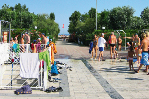 Personas disfrutan del sol y charlan cerca de duchas exteriores en Camping Village Marina di Venezia, Italia.
