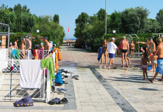 Persone si godono il sole vicino alle docce esterne al Camping Village Marina di Venezia, in Veneto, Italia.