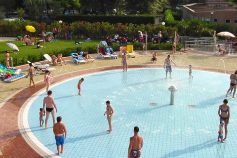 Famiglie e bambini giocano in una piscina poco profonda al Camping Village Marina di Venezia, Veneto, Italia.